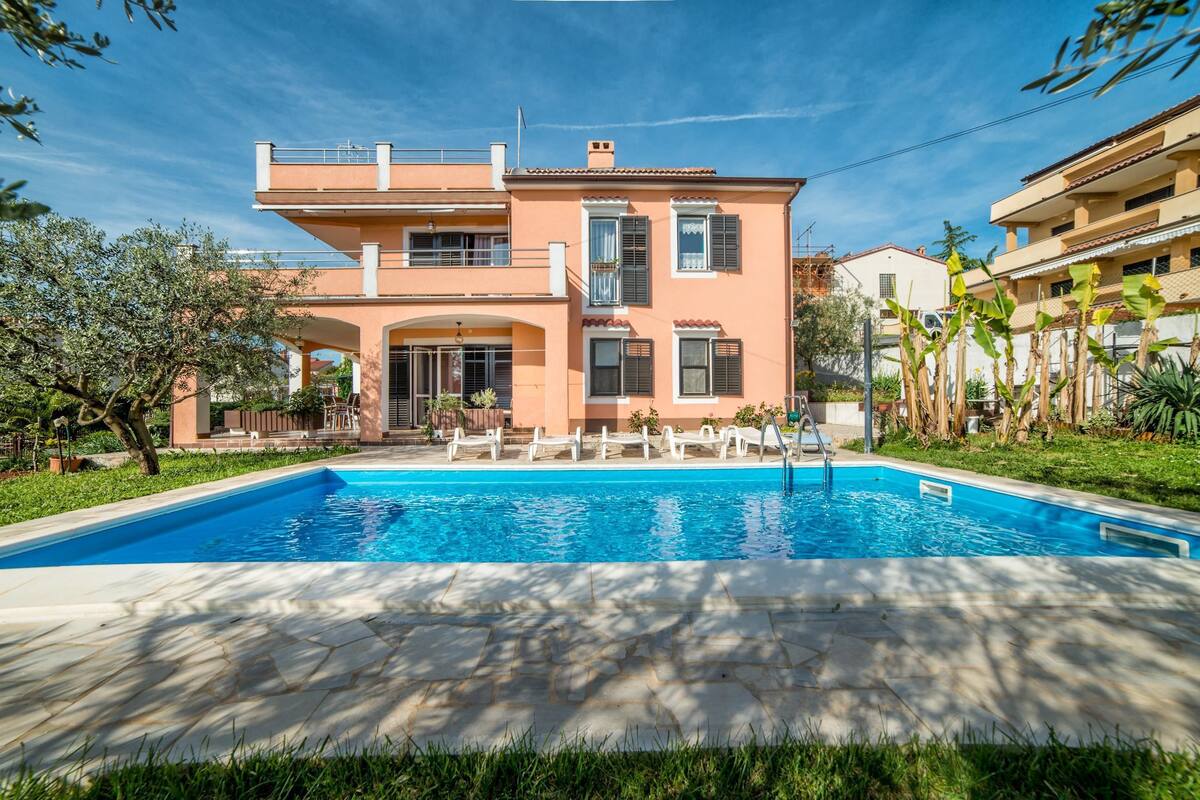 Une maison à deux étages avec une piscine à l’avant.