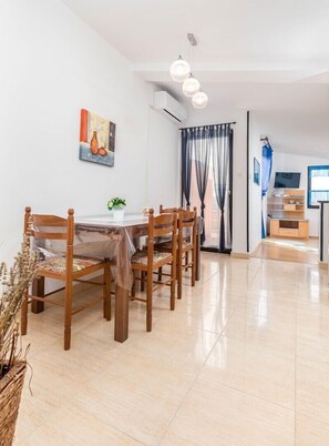A dining area with a table and chairs, a potted plant, and a painting on the wall. - Apartments Marija-samagher (Pula)