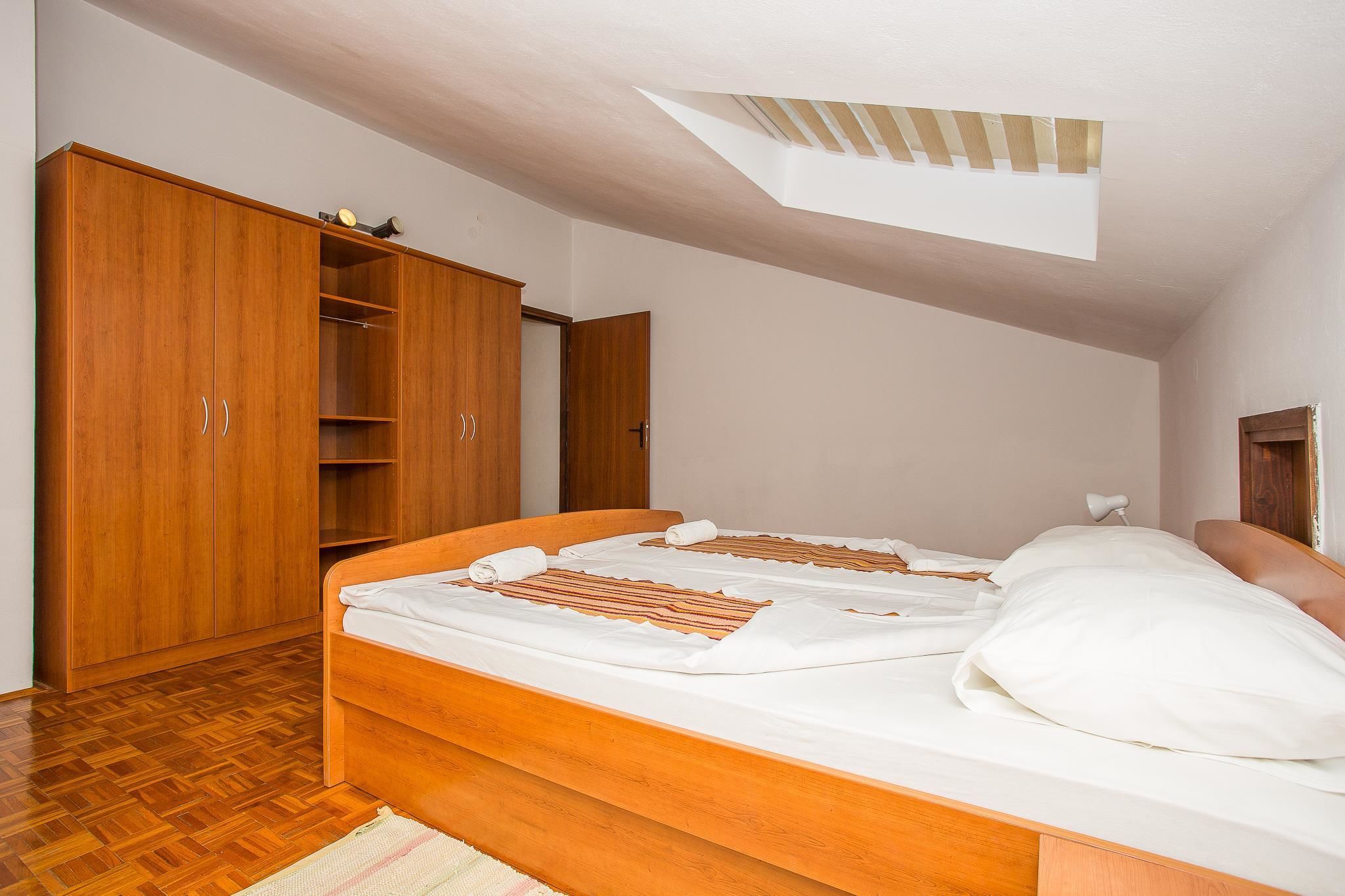 A bedroom with a wooden bed, a wardrobe, and a skylight.