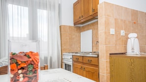 A kitchen with wooden cabinets, a stove, and a coffee maker. - Apartments Adria (Zadar)