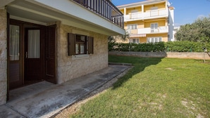 A two-story building with a balcony, a stone facade, and a well-maintained lawn. - Apartments Adria (Zadar)