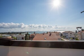 Een woongebied met rode pannendaken, een heldere lucht en een vergezichte op zee en bergen.