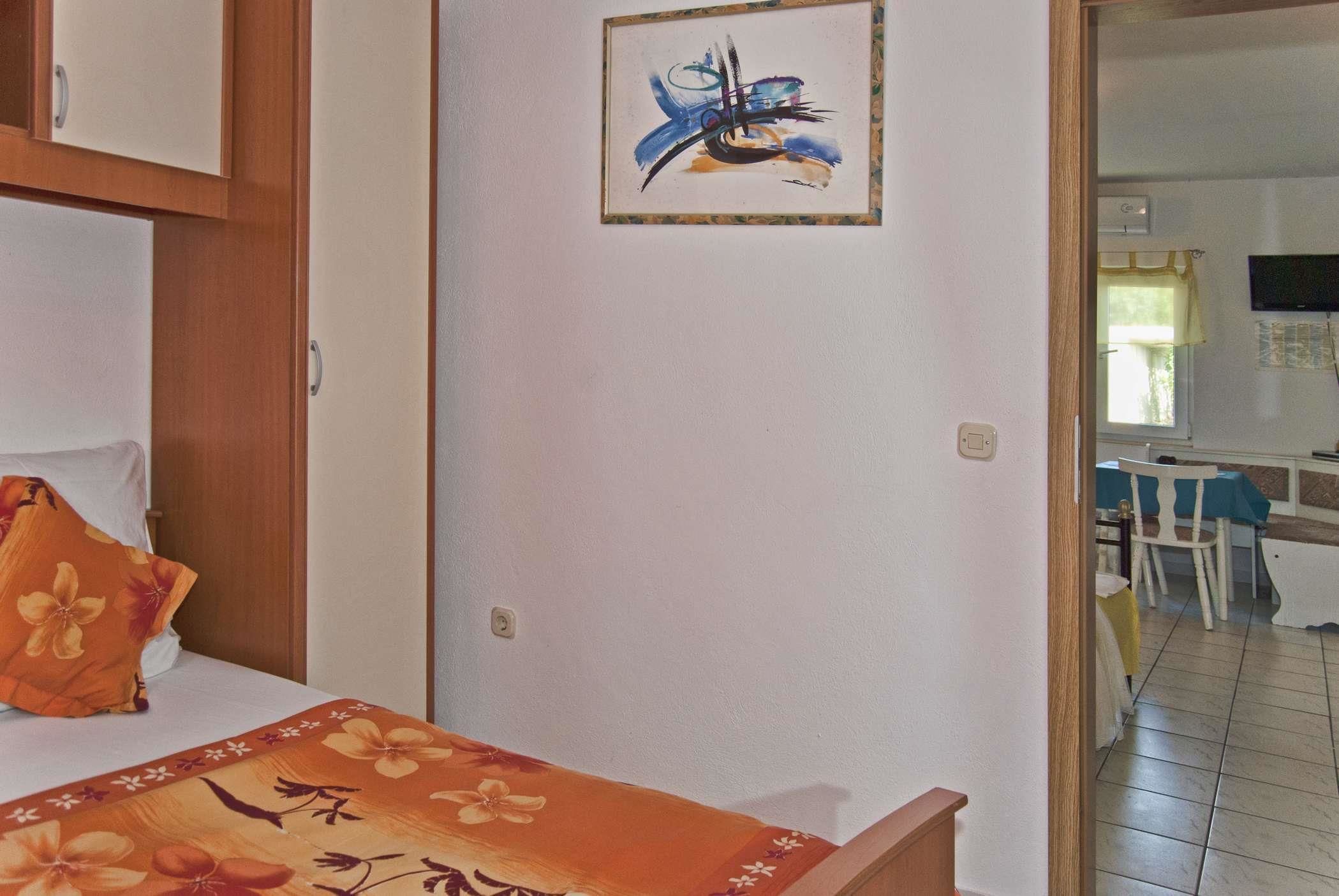Une chambre à coucher avec un lit, une couvre-lit à motifs floraux, un tableau au mur et une vue sur la salle à manger.