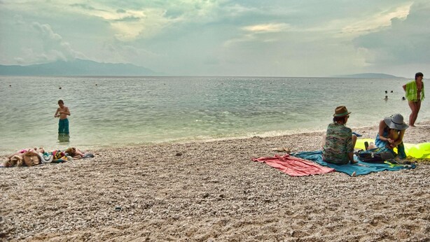 A beach with people relaxing and swimming.