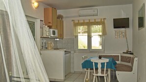 A compact kitchen with a microwave, coffee maker, and a small dining area with a table and chairs.