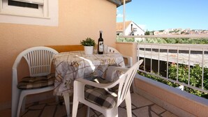 A balcony with a table, chairs, a bottle, and a potted plant. - Apartments Skarpa (Rogoznica)