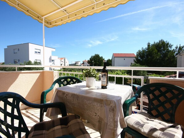 A terrace with a table, chairs, a bottle of wine, and a potted plant. - Apartments Skarpa (Rogoznica)