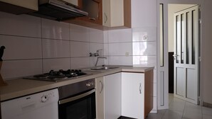 A kitchen with white cabinets, a stove, an oven, and a sink.