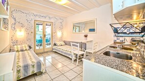A compact room with a bed, a small table, a chair, and a kitchenette. - Apartments Paliaga (Rovinj)