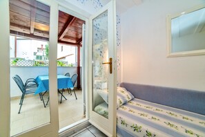 An open door leading to an outdoor patio with a table and chairs, a sofa inside, and a window with a view of the outside. - Apartments Paliaga (Rovinj)