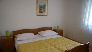 A bedroom with a wooden bed, two bedside tables, and a painting on the wall. - Apartments Ivan Rogoznica (Rogoznica)