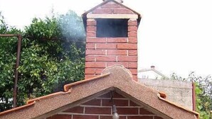 A brick-built outdoor oven with a chimney, a green bowl, and cooking utensils on the grill. - Apartments Ivan Rogoznica (Rogoznica)