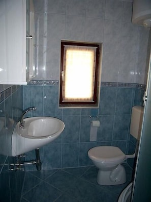 A bathroom with a sink, toilet, and a framed window.