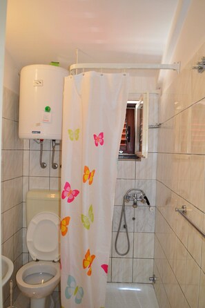 A bathroom with a toilet, a shower, and a toilet paper holder. - Apartments Branko / Joanna / Two Bedrooms (Tribunj)