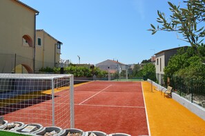 An outdoor tennis court with a net, surrounded by a fence, and adjacent to buildings. - Apartments Branko / Joanna / Two Bedrooms (Tribunj)