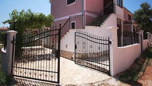 A two-story house with a pink facade, a gated entrance, and a staircase leading to the upper floor. - Istrian Villa Iva (Medulin)