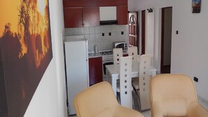 A compact kitchen with a refrigerator, microwave, and stove. There are two beige chairs and a dining table. - Istrian Villa Iva (Medulin)