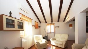 A living room with wooden flooring, a sofa, a chair, a cabinet, and a radiator. - Istrian Villa Iva (Medulin)