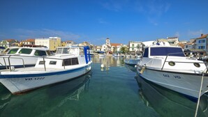 A marina with boats docked, clear water, and buildings in the background. - Apartments Milenko / Three Bedrooms A2 (Vodice)