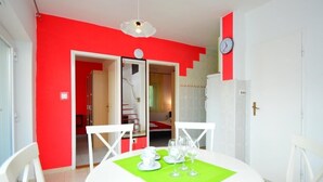 A dining area with a white table and chairs, a green placemat, and a red accent wall. - Holiday House Tina Tribunj (Tribunj)