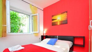 A hotel room with a bed, a window with curtains, a red wall, and a painting. - Holiday House Tina Tribunj (Tribunj)