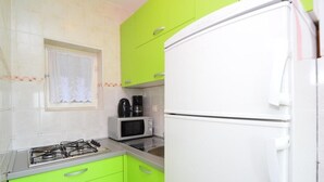 A kitchen with green cabinets, a white refrigerator, a gas stove, and a microwave. - Holiday House Tina Tribunj (Tribunj)