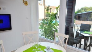 A dining area with a round table, white chairs, and a green placemat. - Holiday House Tina Tribunj (Tribunj)