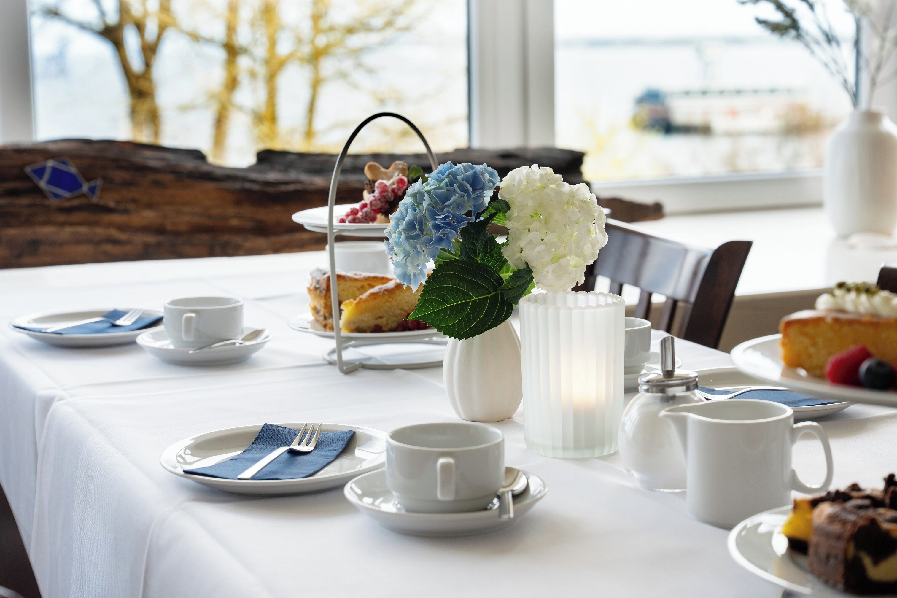 A table set for breakfast with plates, cups, and a vase of flowers.