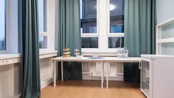 A room with a white table, green curtains, a white radiator, and a white cabinet.