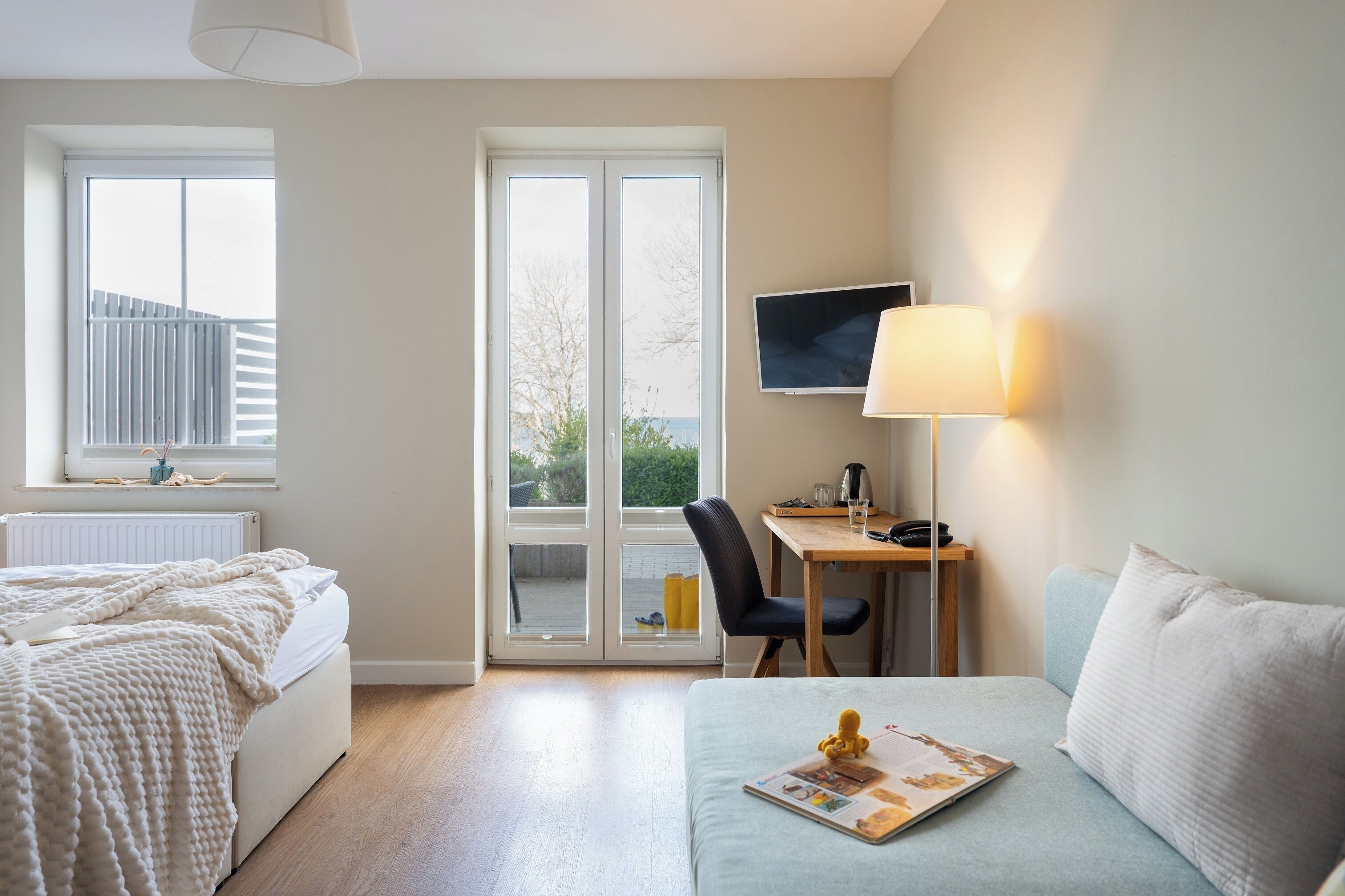 A bedroom with a bed, a desk, a chair, a sofa, and a TV.