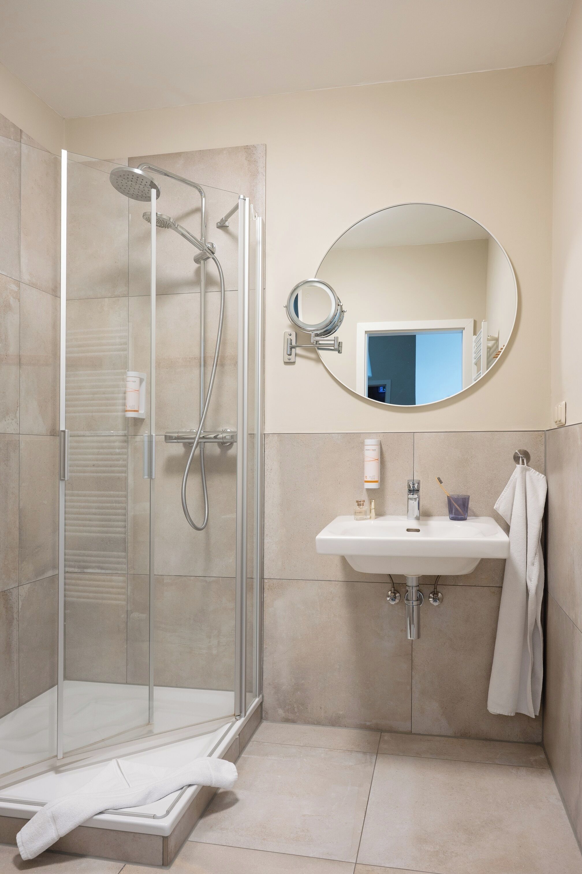 A bathroom with a glass-enclosed shower, a sink with a mirror, and a towel rack.