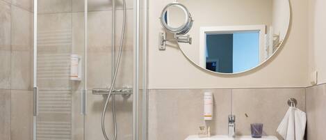 A bathroom with a glass-enclosed shower, a sink with a mirror, and a towel rack.