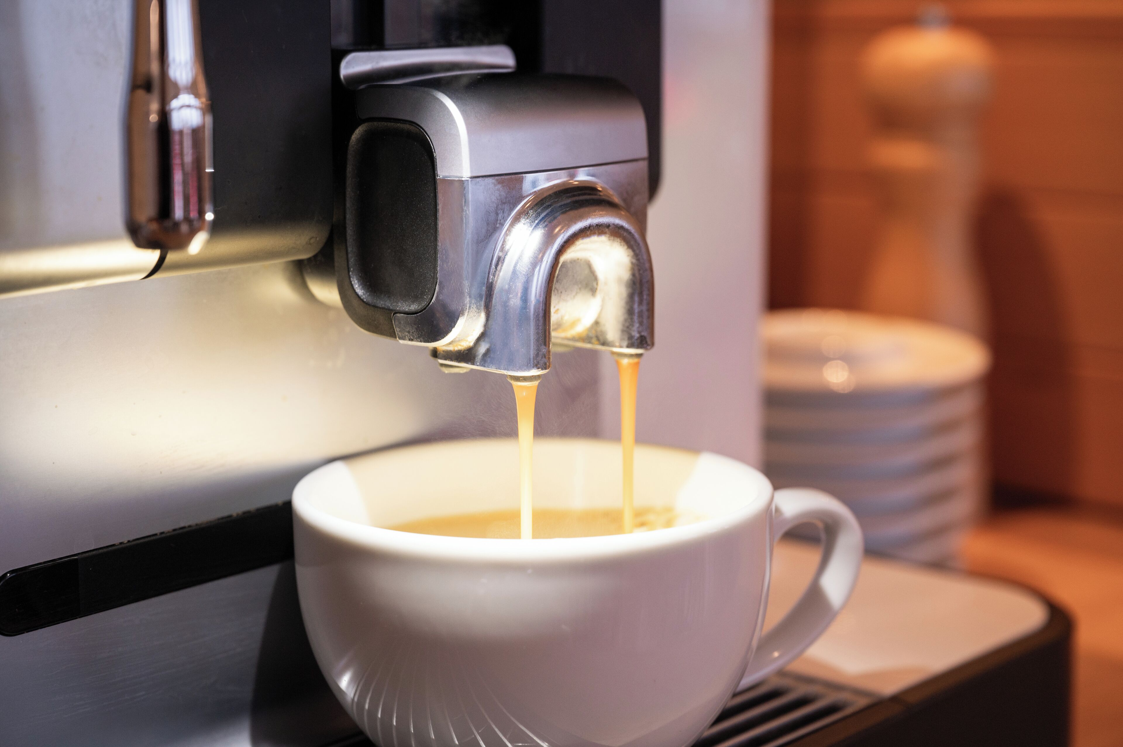 A coffee machine dispensing coffee into a white cup.