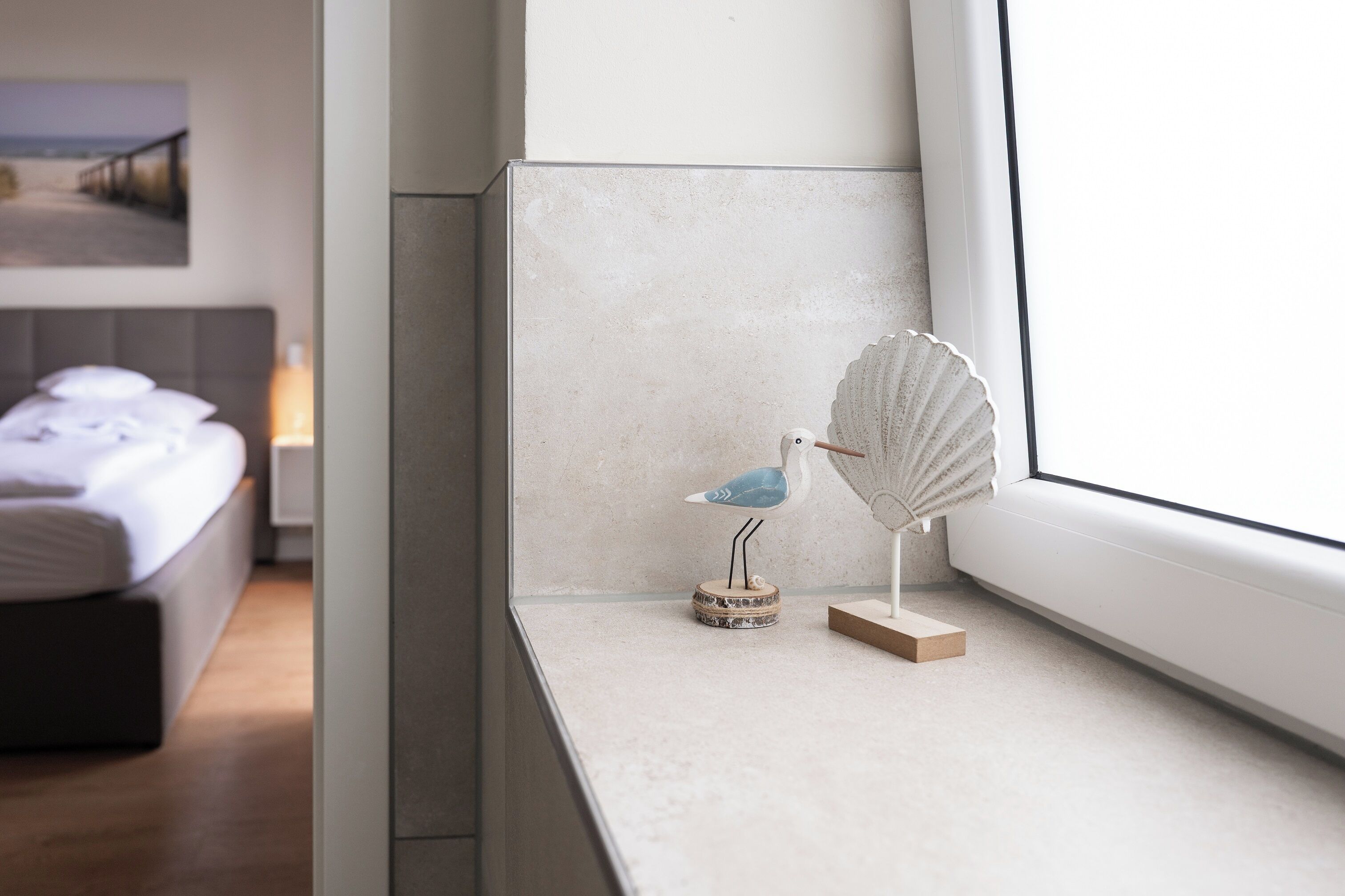 Une chambre à coucher avec un lit, une fenêtre donnant sur un beau paysage et un objet décoratif posé sur le rebord de la fenêtre.