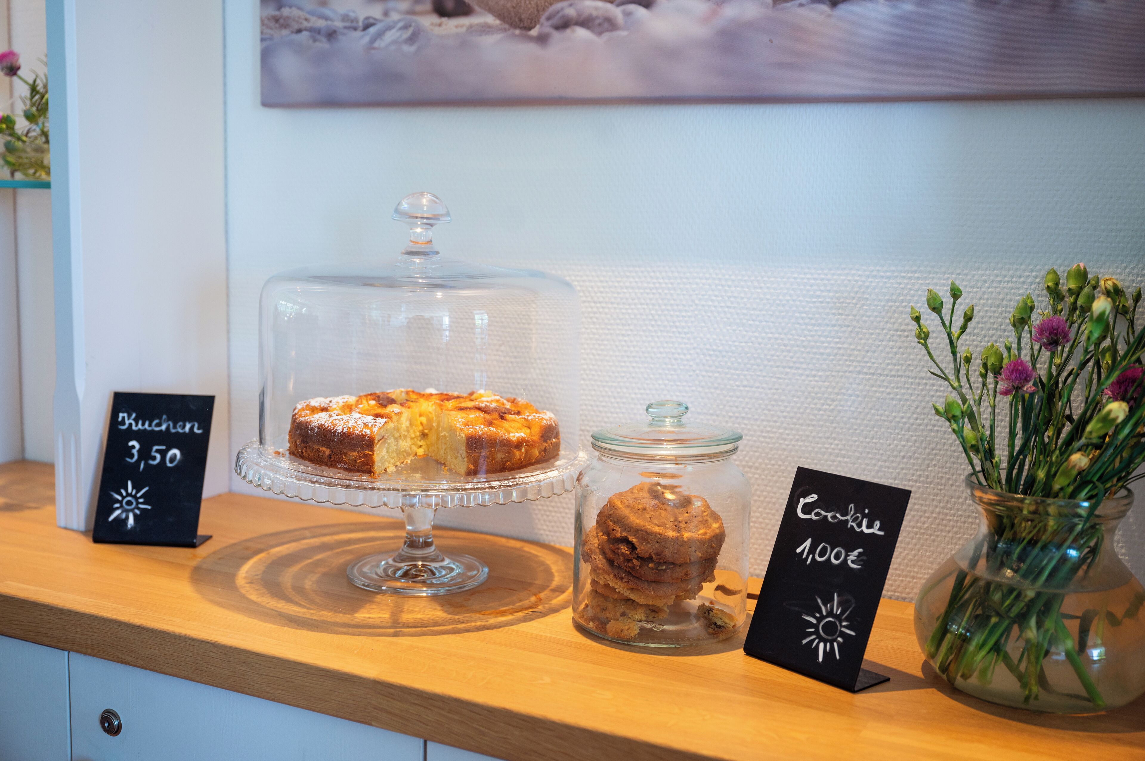 A dessert display with a cake and cookies, each with a price tag.
