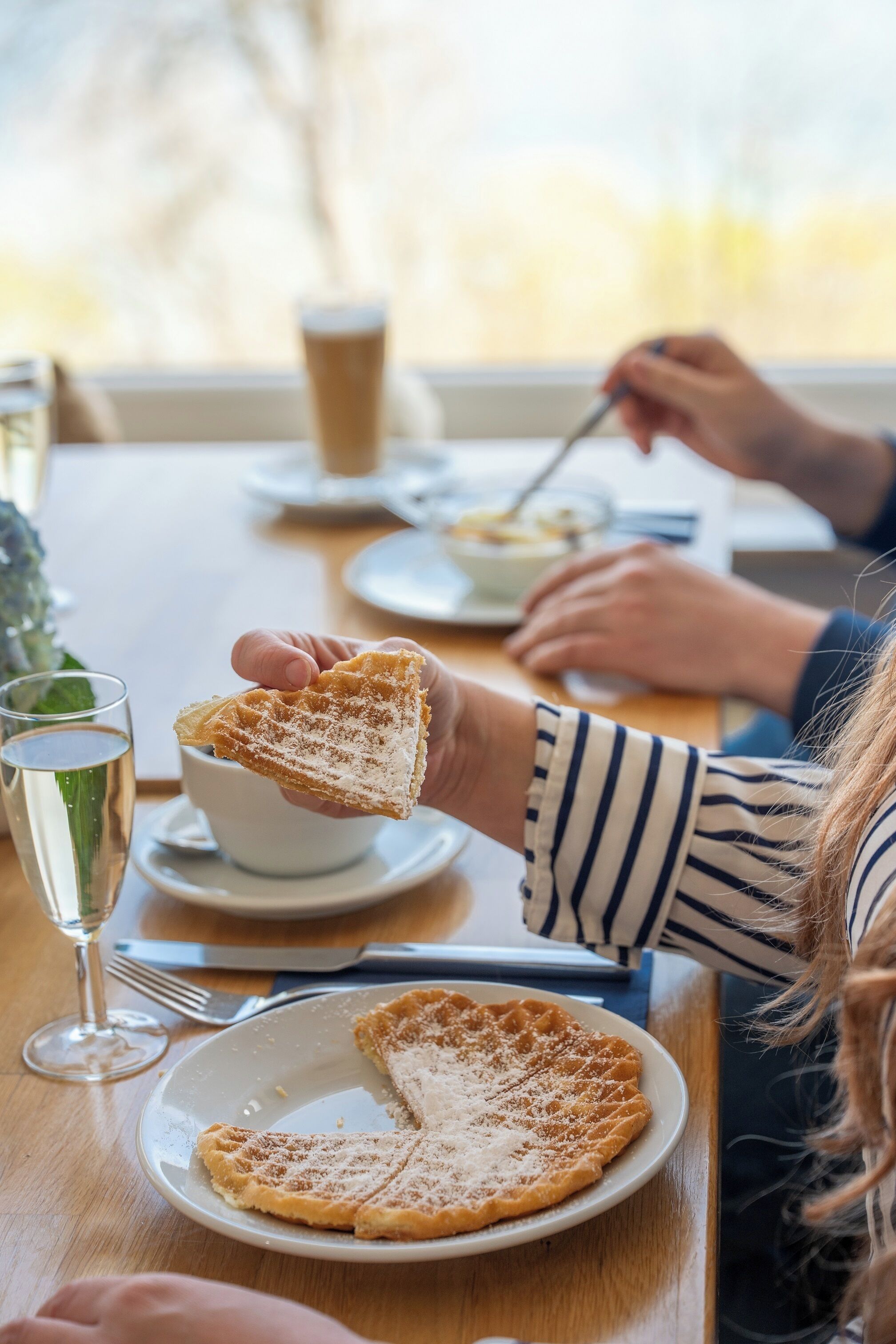 Una mesa de comedor con un plato de comida, un vaso de agua y una taza.