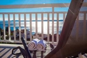 A balcony with a view of the sea, a chair, and rolled towels. - Apartments Marija Sego (Okrug)