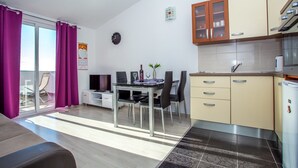 Eine moderne Wohnung mit Essbereich, Küchenzeile und einem Balkon mit violetten Vorhängen.