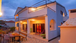 A two-story house with a stone patio, a balcony, and a dining area with outdoor furniture. - Villa Diana Razanj (Rogoznica)