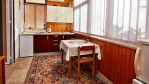 Une cuisine compacte avec des meubles de rangement en bois, un petit réfrigérateur et une table à manger pour deux personnes.