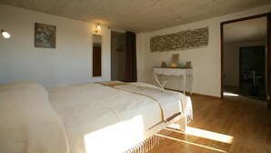 Un dormitorio con una cama grande, un escritorio pequeño, un muro de piedra y un espejo.