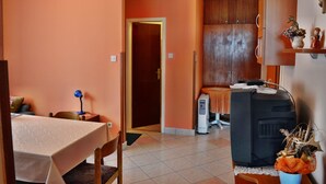 Ein Zimmer mit Esstisch, Stühlen, Fernseher und Schrank.