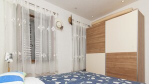 A bedroom with a bed, curtains, a lamp, and a wardrobe.