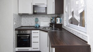 A modern kitchen with white cabinets, a built-in oven, and a stainless steel range hood.