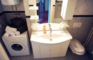 A compact hotel bathroom with a Bosch washing machine, a sink with a mirror, and a toilet. - Family Apartment Teo (Split)
