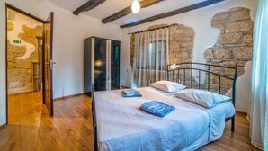 Camera da letto con un letto, travi in legno, pareti in pietra, un armadio e una porta con una mappa.