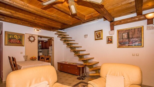 Un salon avec un escalier en bois, des canapés en cuir et un coin repas comprenant une table et des chaises.
