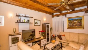 Un salon avec un plafond en bois, une télévision, un canapé, une table basse et des objets décoratifs disposés sur des étagères.