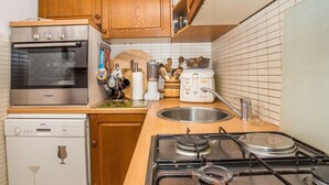 Une cuisine compacte équipée d’un four Bosch, d’un lave-vaisselle et d’une cuisinière à gaz.