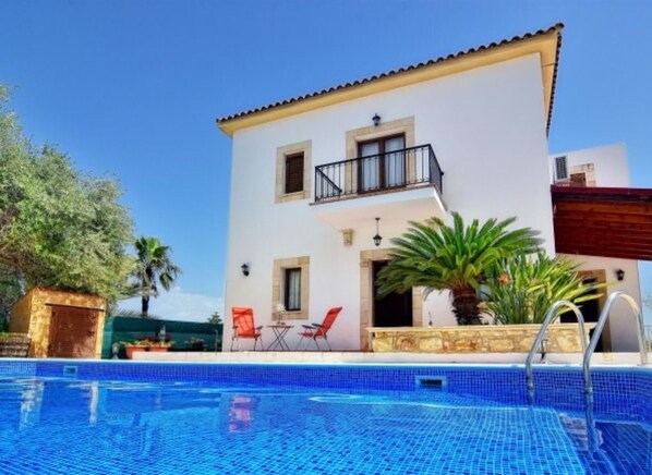 A two-story building with a balcony, a swimming pool, and outdoor seating.